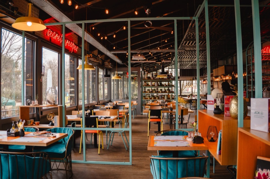 Restaurant-Innenraum der Denkfabrik mit türkisen Stühlen und Fensterfront